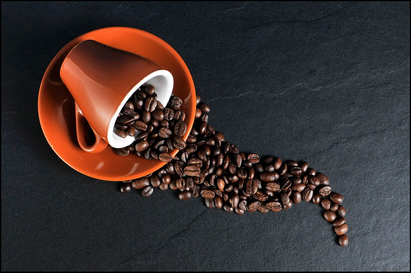 Roasted coffee beans spilling from a cup