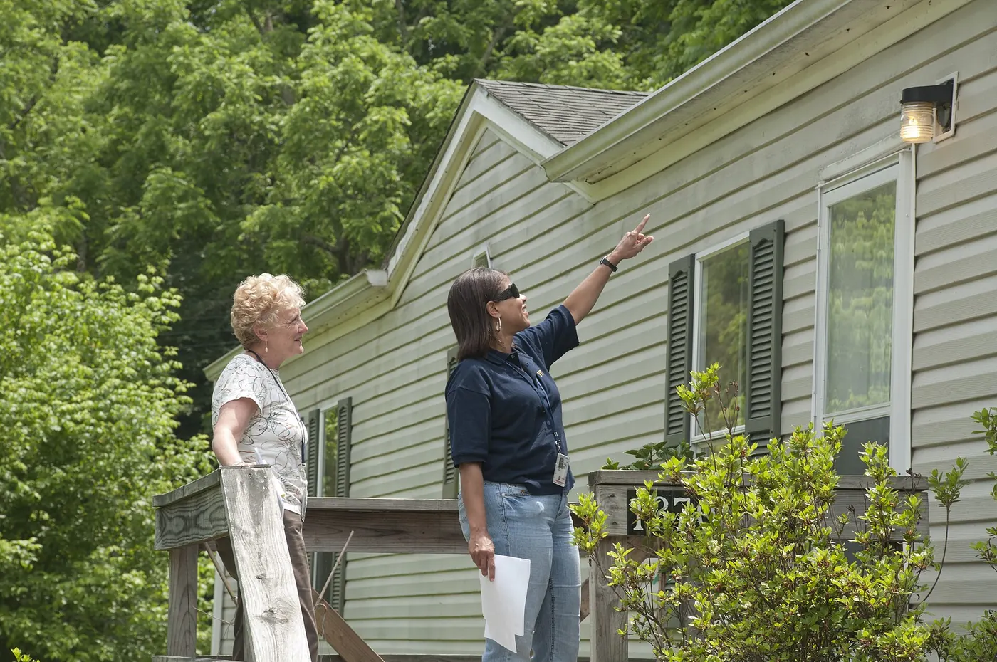 Two people inspecting the outside of a house