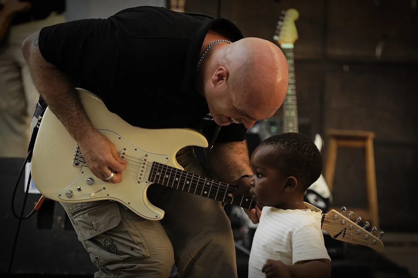 A guitar teacher showing a child how to play